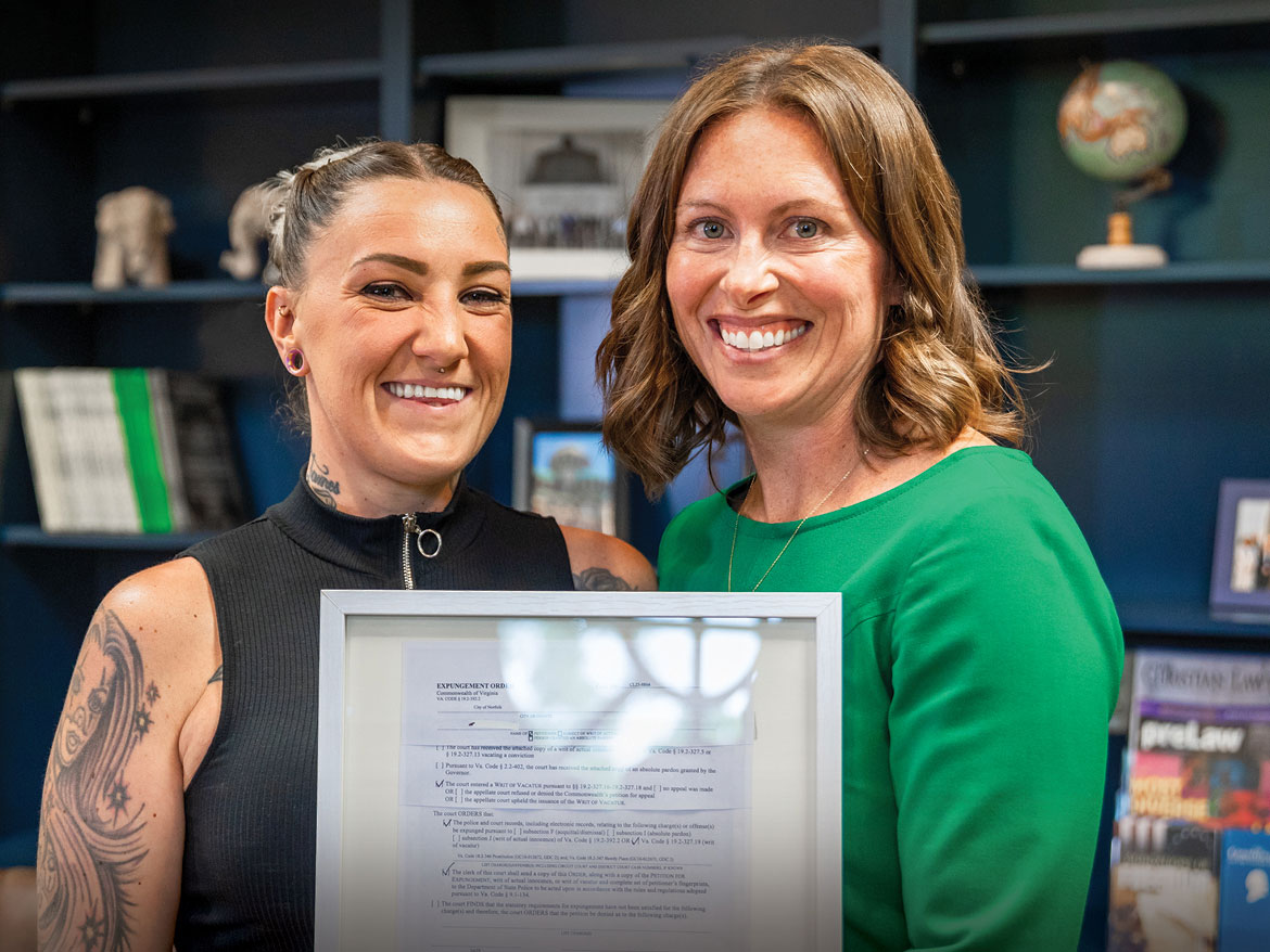 Photo of Olivia, a Trafficking survivor, holding a framed document with her lawyer: Learn more about Regent's center for global justice clinic.