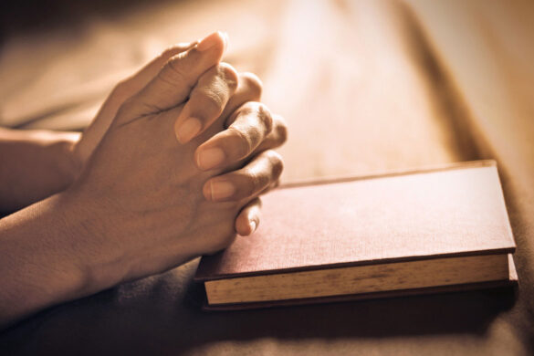 hands praying on bible